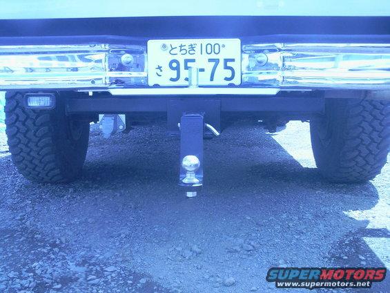 Rear view of a vehicle showing a trailer hitch with a ball mount and a license plate